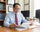 Man sitting at a desk in an office, reviewing documents.