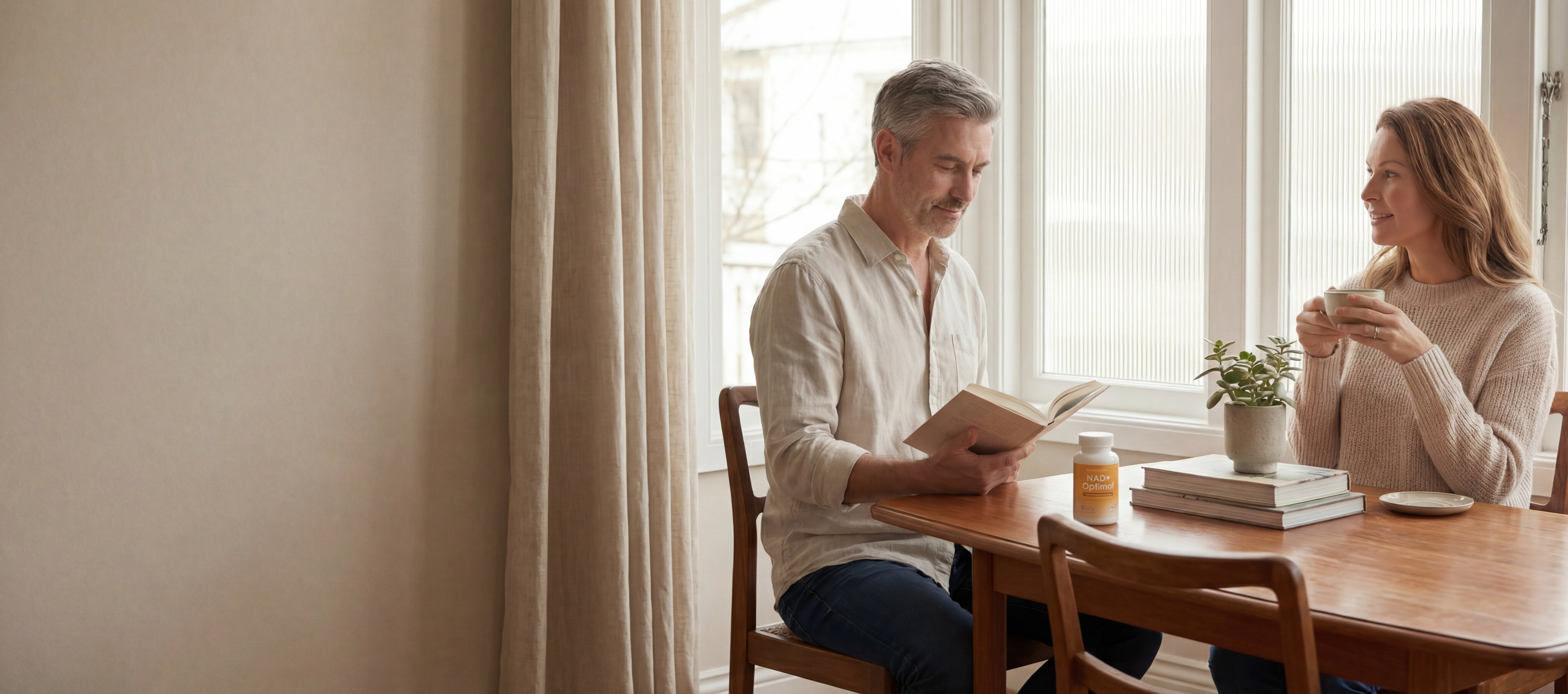 Man and woman sitting at a table with books and a coffee cup, engaged in conversation.