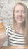 Woman holding a bottle of Optimal NAD+ supplement in front of a floral-patterned wall.